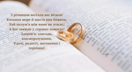 Два золоті кільця на відкритій книзі з привітанням.
