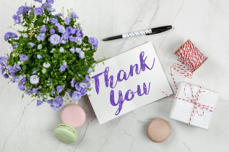 Картка з написом Thank You серед квітів та цукерок.